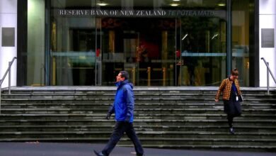 NZ central bank holds rates, tones down hawkish stance